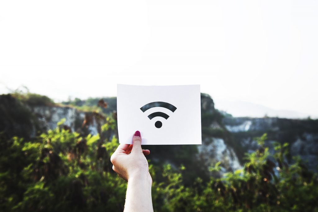 wifi signal image on paper held up in front of mountains in background